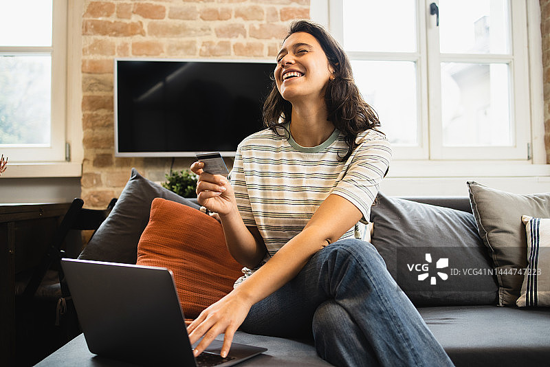 快乐的年轻女人使用信用卡进行在线购物图片素材