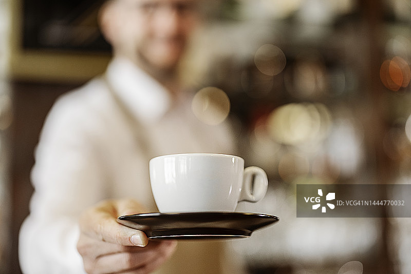 服务员端着卡布奇诺咖啡的特写图片素材