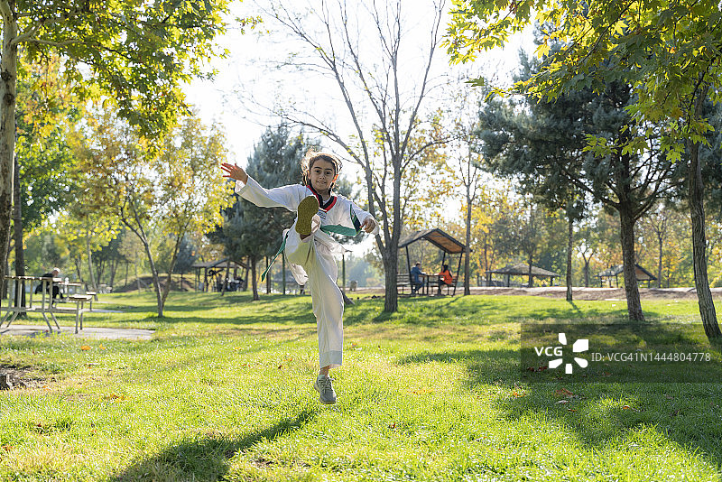 女孩在公园草地上进行跆拳道训练图片素材