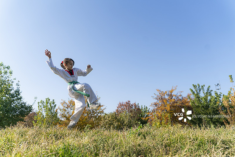 女孩在公园草地上进行跆拳道训练图片素材