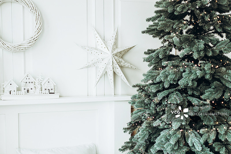 白色墙壁前的圣诞树与3D星星和玩具屋图片素材