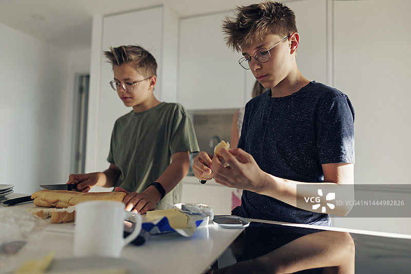 母亲和青少年儿子们在早上准备早餐图片素材