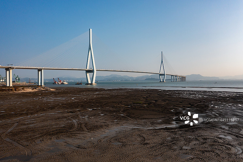 阳光下的海滩和跨海大桥图片素材