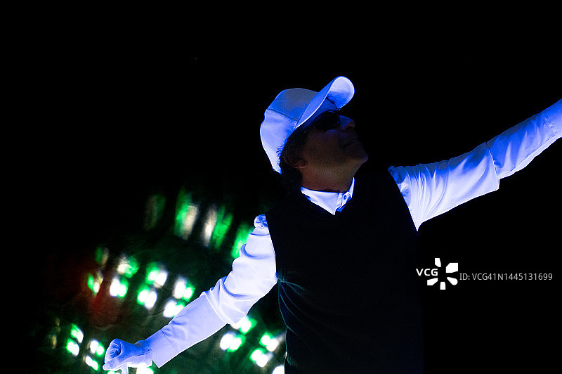 迪斯科舞厅里戴着白色面具跳舞的西装男子：紫外线照明图片素材