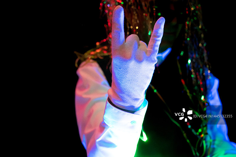 迪斯科舞厅里跳舞的人做摇滚手势特写，紫外线照明图片素材
