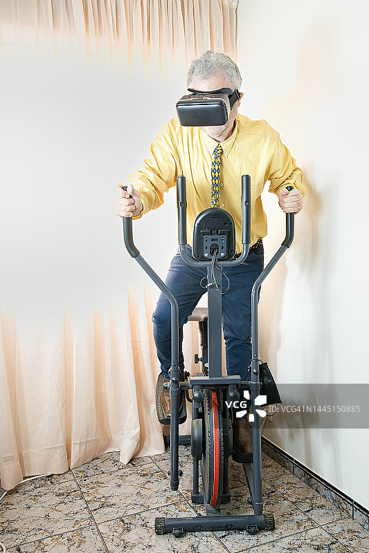 戴VR眼镜在椭圆机上锻炼的商人图片素材