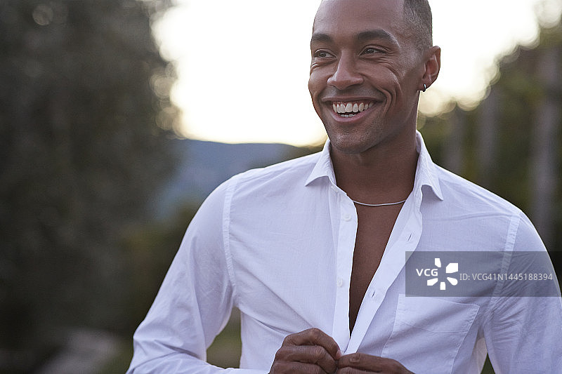 快乐的年轻男人在扣白色衬衫的扣子图片素材