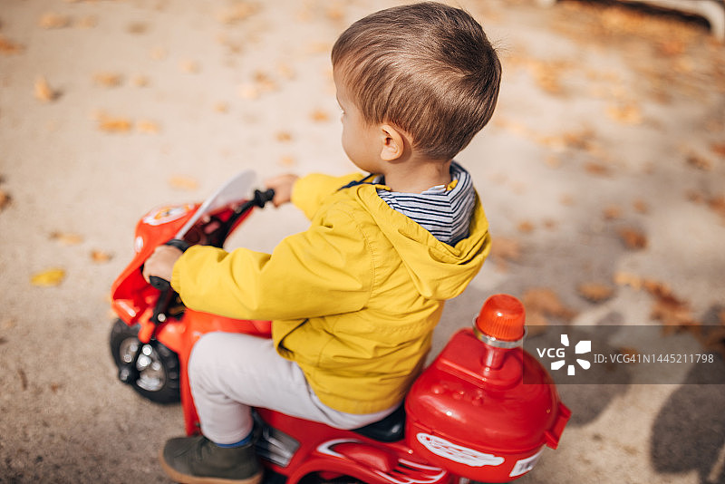 小男孩骑玩具摩托车图片素材