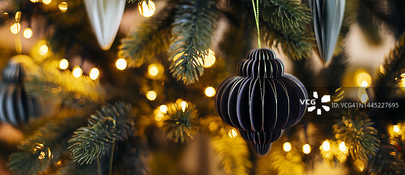 圣诞树上的米色和绿色纸玩具，背景是花环灯，新年概念网站banner设计图片素材