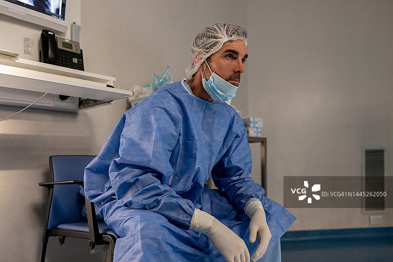 外科医生坐在手术室的椅子上，看起来很疲惫图片素材