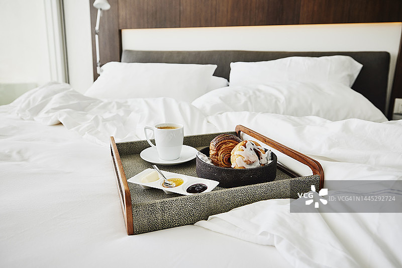 酒店房间里未整理的床上的早餐托盘半身照图片素材