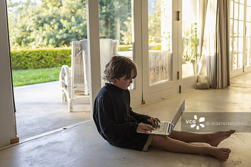 坐在地板上使用笔记本电脑的男孩（8-9岁）图片素材