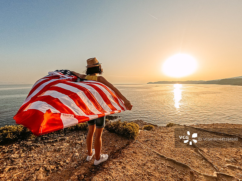 年轻女人在海滩挥舞美国国旗图片素材