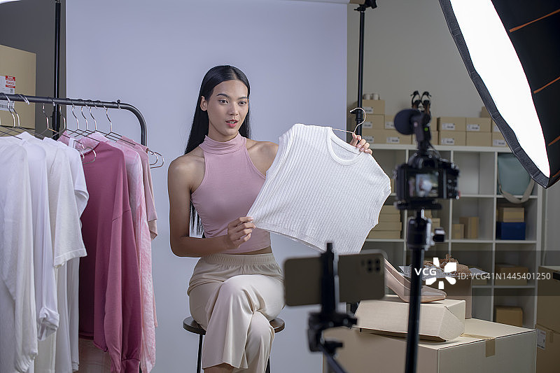 在工作室仓库通过社交媒体在线销售服装的亚洲女人图片素材