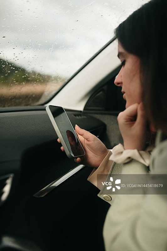 在车里拿着智能手机的女人图片素材