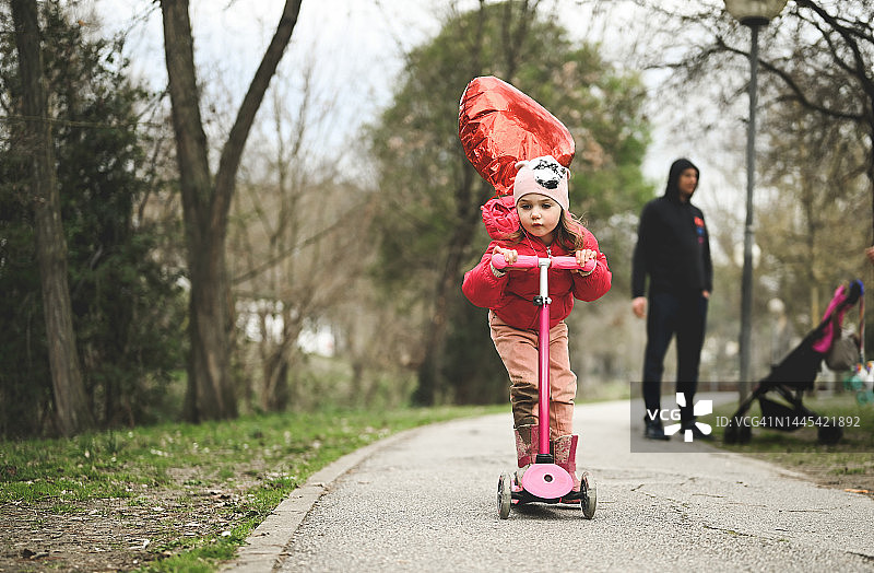 冬天在公园里骑滑板车的快乐女孩图片素材