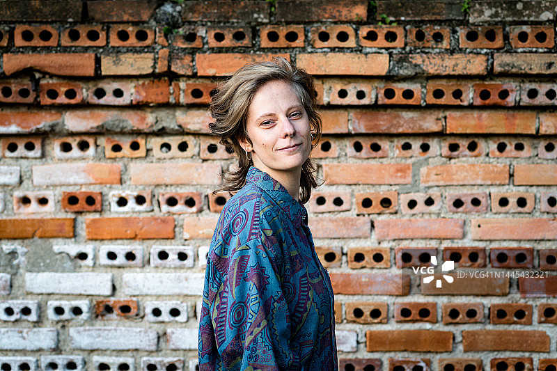 靠在砖墙上的美丽年轻女子肖像图片素材