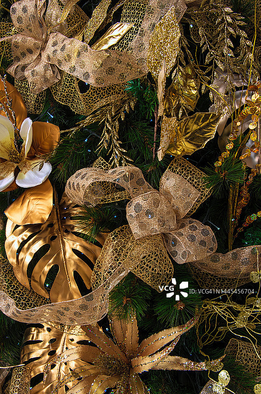 用金色丝带和花卉装饰品装饰的人造圣诞树图片素材