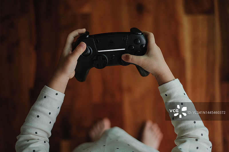 亚洲小女孩在家玩电子游戏的俯视图图片素材