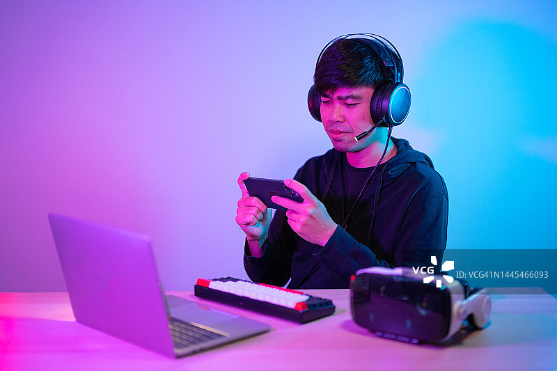 在家玩手机游戏的年轻亚洲男子图片素材