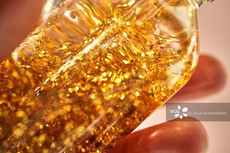 一位女士手中的一瓶含金颗粒精华液图片素材