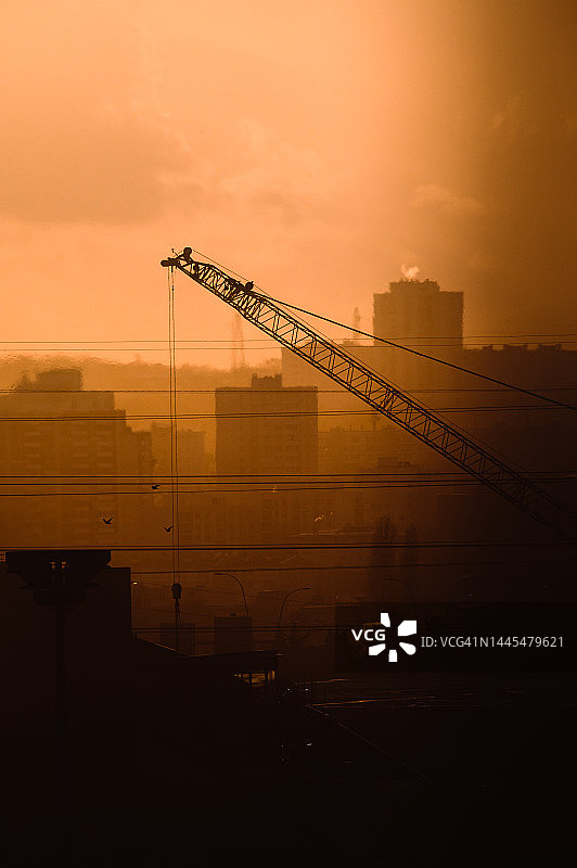 城市中央建筑起重机上的橙色日落图片素材