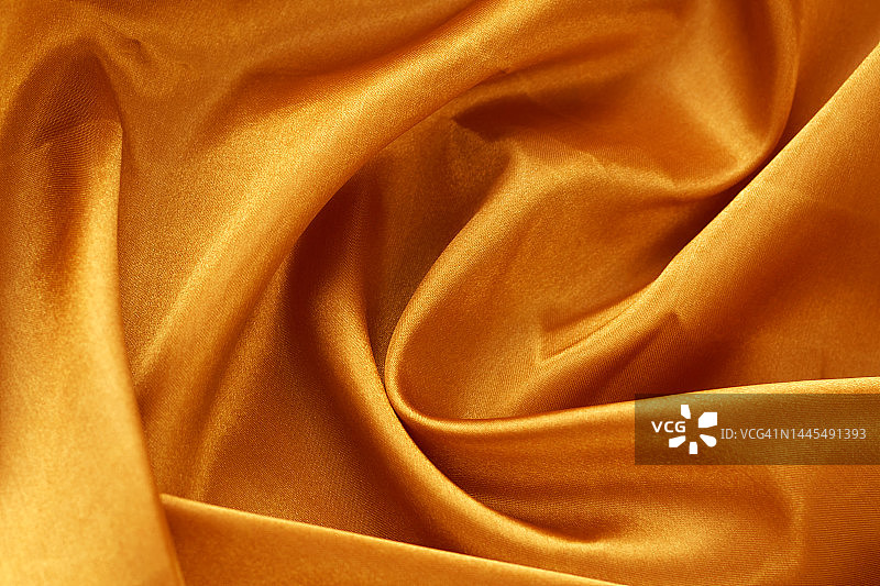 金色缎面纹理背景，波浪和褶皱，奢华产品展示用黄色布料背景，特写图片素材