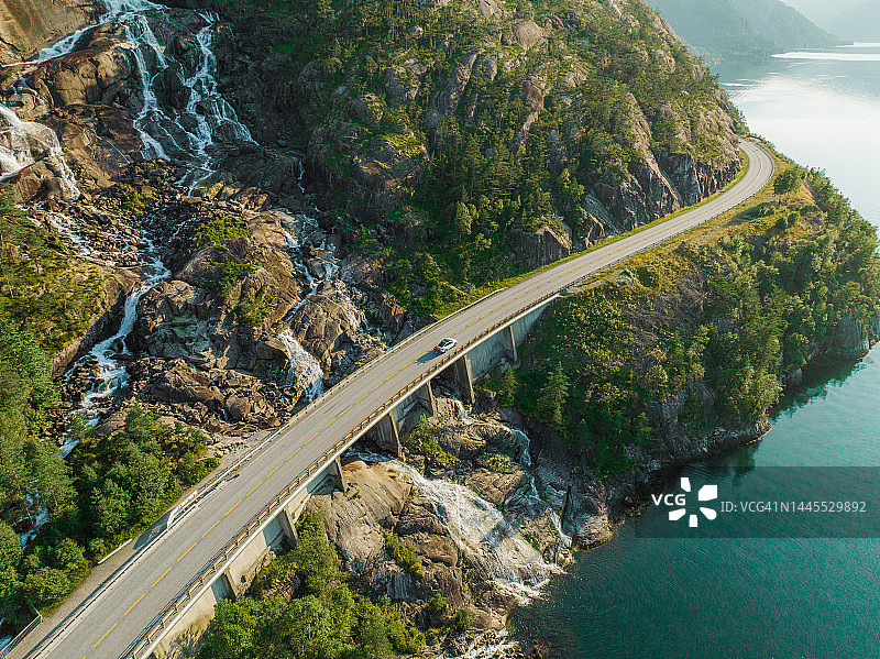 挪威，瀑布流入峡湾附近道路上的汽车航拍视角图片素材