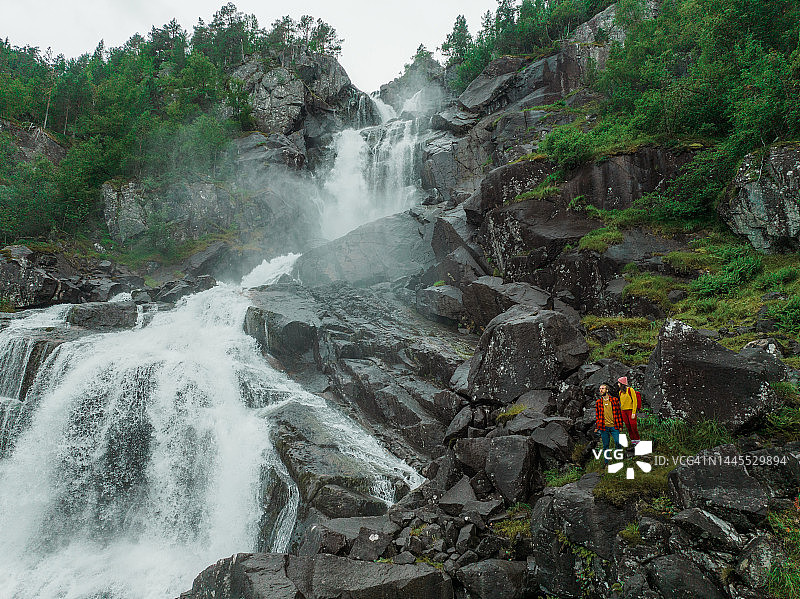 挪威山区瀑布附近的一对男女航拍图片素材