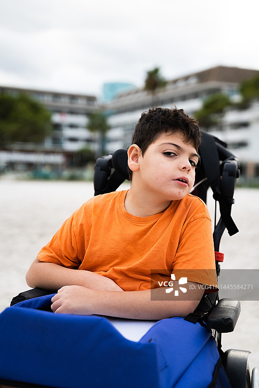 坐在海滩轮椅上的四肢瘫痪男孩图片素材