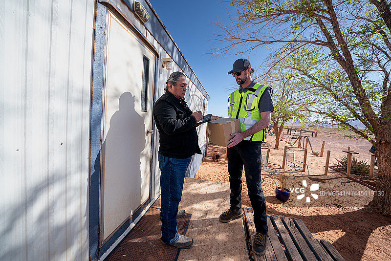 男子在小镇的组合房屋里给老年男子送包裹图片素材