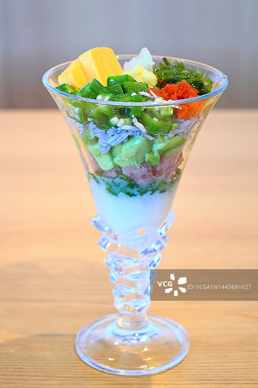 海鲜：鸡尾酒杯中的寿司和刺身，木桌，飞鱼籽鱼子酱、秋葵、海藻和玉子烧配料图片素材