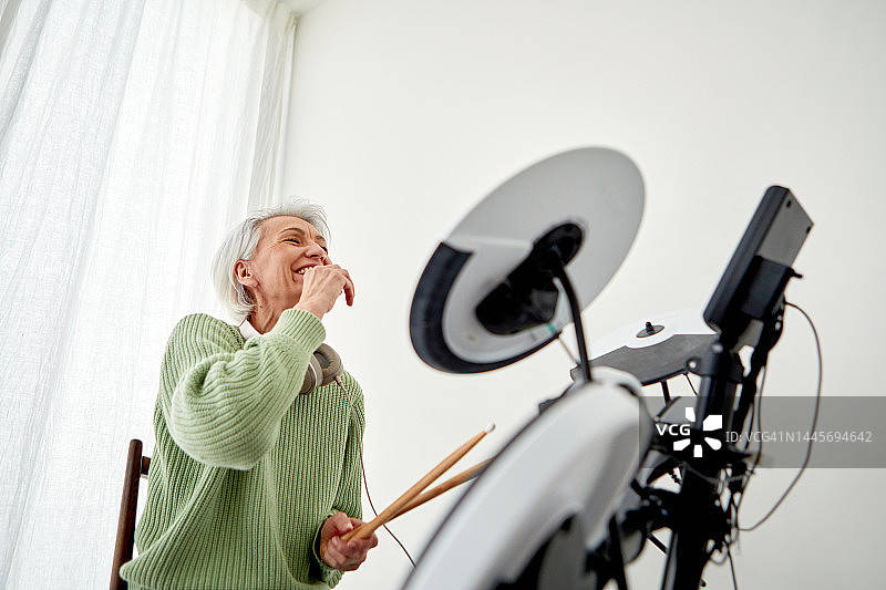 快乐的老年妇女在工作室里演奏钹图片素材