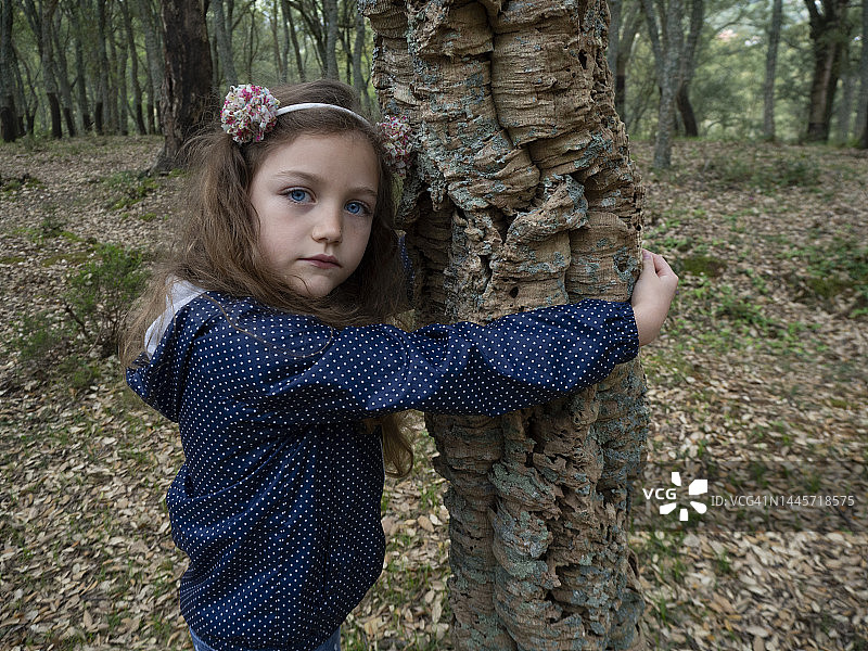 女孩站在意大利的森林里，拥抱一棵栓皮栎树图片素材