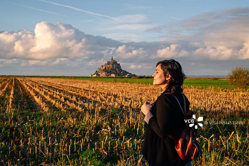 日落时分，背包游客女子在圣米歇尔山草甸的水平全景照片图片素材