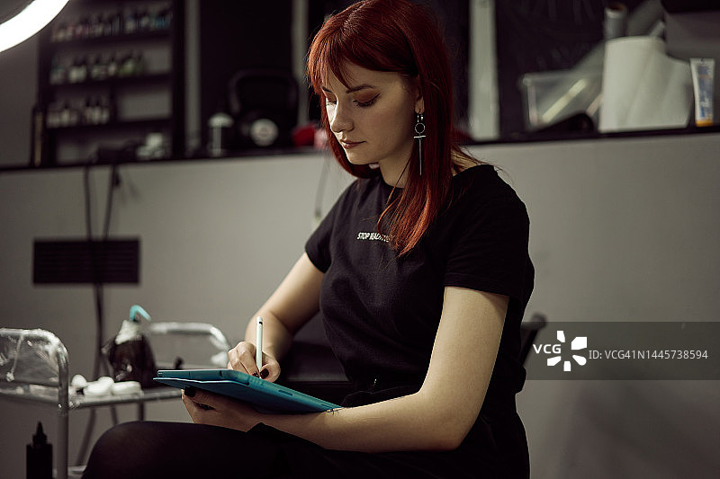 在纹身工作室用数位板绘画的女人图片素材