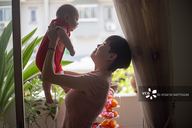 中国新年期间抱着婴儿的亚洲母亲图片素材