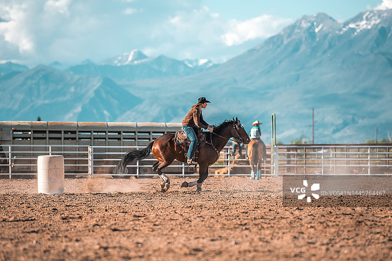 年轻女牛仔骑马绕桶赛图片素材