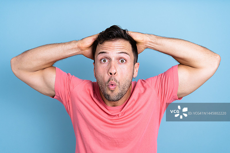 震惊的男人在蓝色背景下看着镜头图片素材