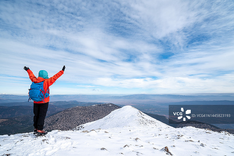 女登山者庆祝成功，张开双臂欣赏山顶美丽的森林和山脉图片素材
