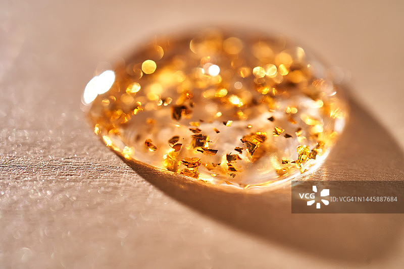 带有金色颗粒的精华液滴质地图片素材
