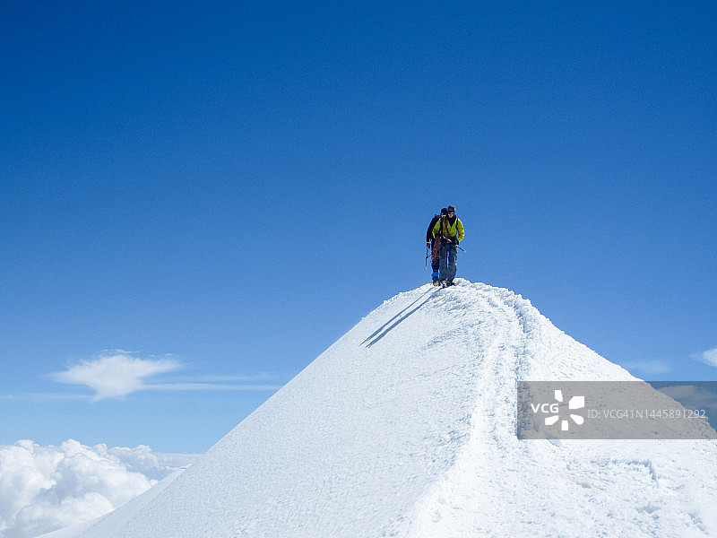 登上雪山顶峰的登山者图片素材