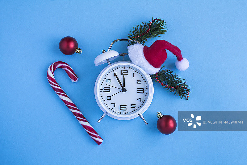 蓝色背景上的圣诞老人帽白色闹钟顶视图，留白区域图片素材