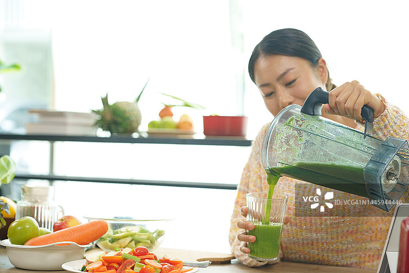 健康的女人制作绿色果汁饮用图片素材