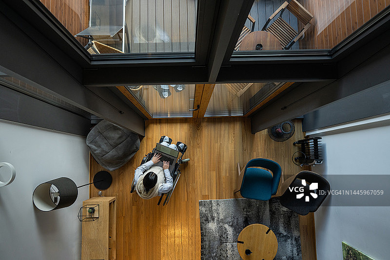 年轻女子在家中坐在轮椅上使用笔记本电脑图片素材