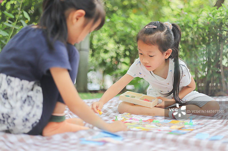 两个女孩在野餐垫上玩大富翁游戏图片素材