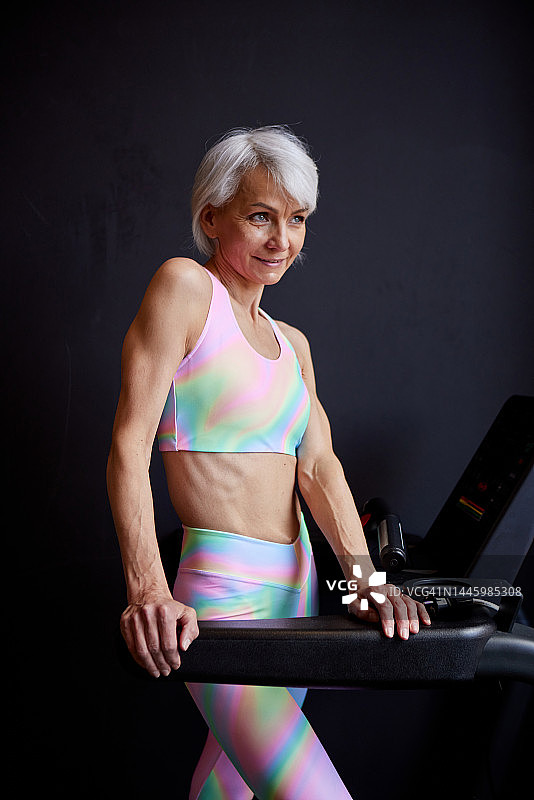 快乐的女运动员在跑步机上转动图片素材