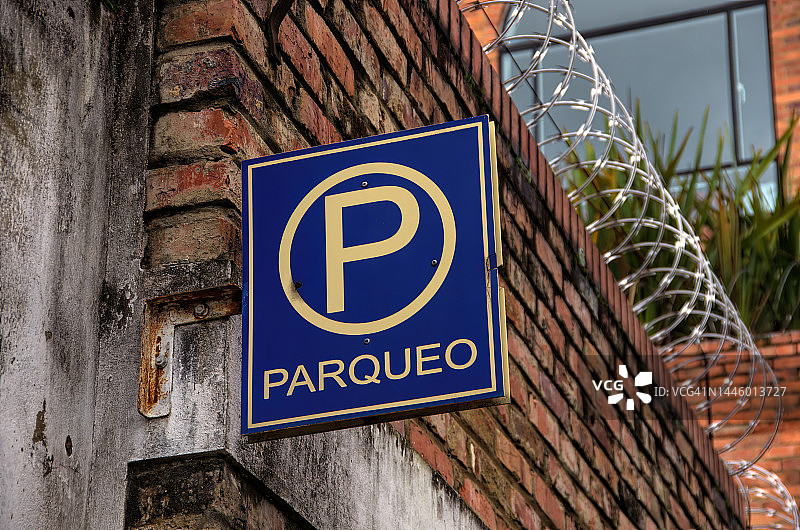 围墙停车场上的西班牙语“Parqueo”[停车处]标志图片素材