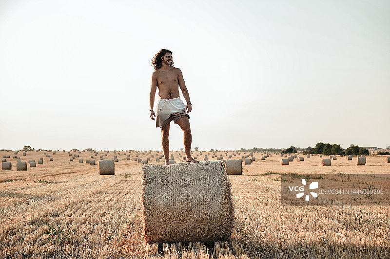 田野干草堆上年轻男人拍照图片素材