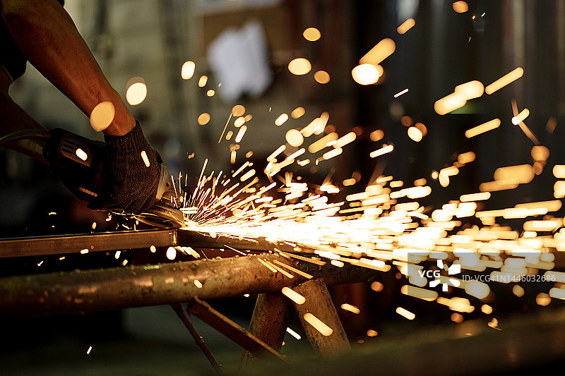 结构与建筑工程：金属工人在金属车间用砂轮锯切割或研磨金属栅格结构框架的特写镜头图片素材